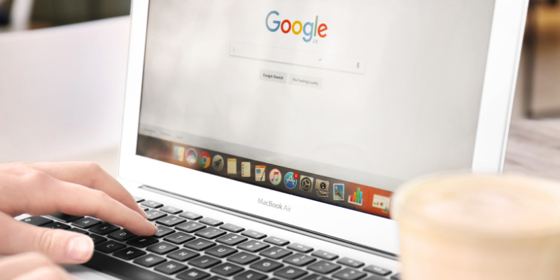 Mano utilizando un portátil con la página de Google abierta, representando campañas publicitarias digitales en Google y Meta para aumentar visibilidad sin grandes presupuestos.