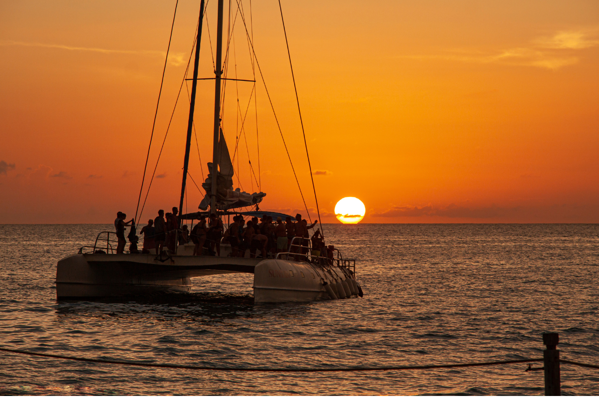 Catamarán navegando al atardecer con pasajeros a bordo